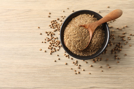 Coriander powder in bowl, spoon and seeds on wooden table, top view. Space for textの写真素材