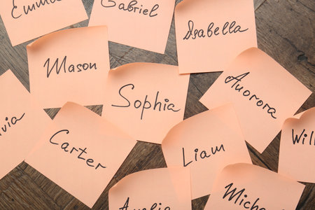 Paper stickers with different names on wooden background, flat lay. Choosing baby's nameの写真素材
