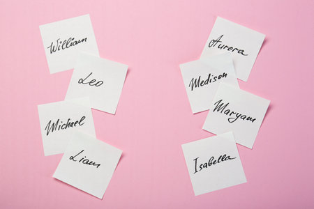 Paper stickers with different names on pink background, flat lay. Choosing baby's nameの写真素材