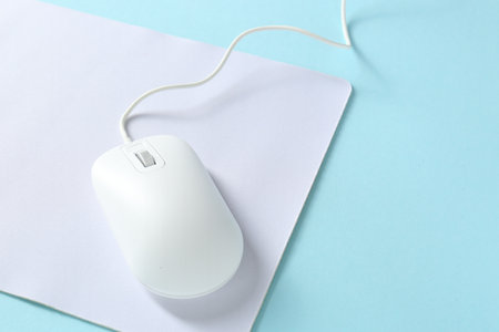 Wired mouse and mousepad on light blue background, space for textの写真素材