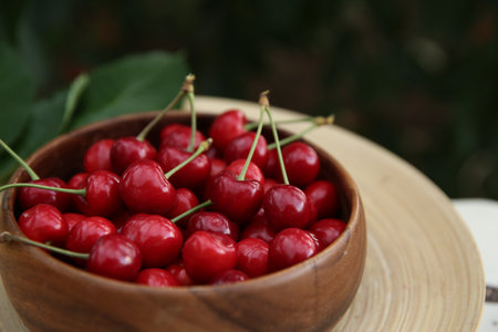 Tasty ripe red cherries in wooden bowl outdoors, closeupの写真素材