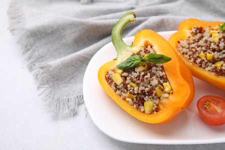 Quinoa stuffed bell pepper with basil and tomato on light table, closeup. Space for textの写真素材