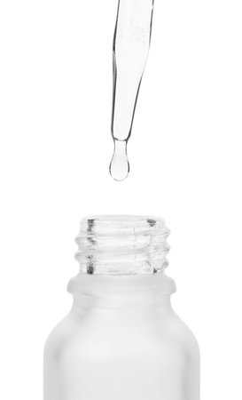Dripping liquid from pipette into bottle isolated on white, closeupの写真素材