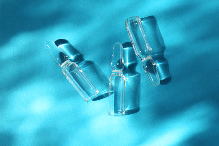 Skincare ampoules in sunlight on light blue background, top viewの写真素材