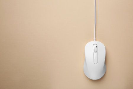 One wired mouse on beige background, top view. Space for text