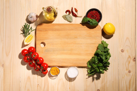 Cutting board surrounded by spices, tomatoes, oil and lemon on wooden table, flat lay. Space for textの写真素材