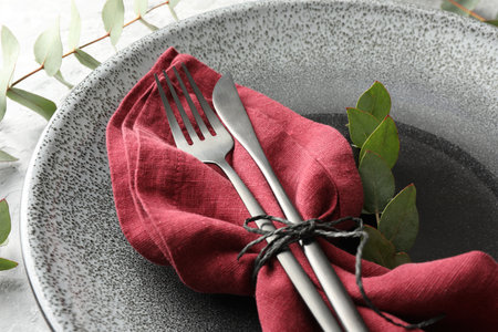 Stylish setting with cutlery, napkin, eucalyptus branches and plate on table, closeupの写真素材