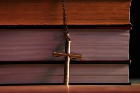 Cross and stack of books on table, closeup. Religion of Christianityの写真素材