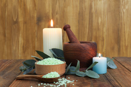 Aromatherapy products, burning candles and eucalyptus leaves on wooden tableの写真素材