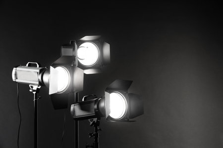 Dark photo background and professional lighting equipment in studio. Space for textの写真素材