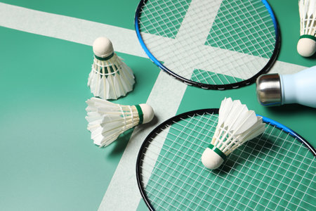 Feather badminton shuttlecocks, rackets and bottle on courtの写真素材