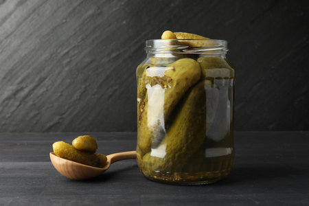 Jar and spoon with pickled cucumbers on gray wooden tableの写真素材