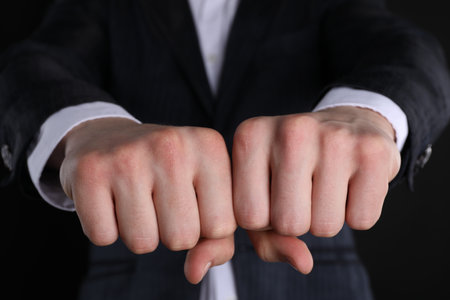Businessman showing fists with space for tattoo on black background, closeupの写真素材