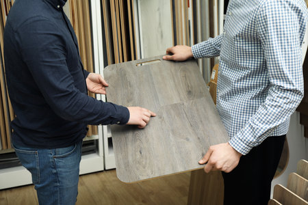 Men holding sample of wooden flooring in shop, closeupの写真素材
