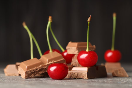 Fresh cherries with pieces of milk chocolate on gray textured table, closeupの写真素材