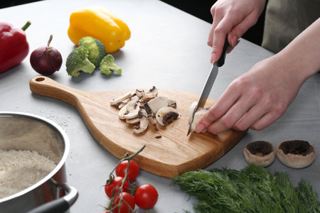 Healthy food. Woman cutting champignon at gray table, closeupの写真素材