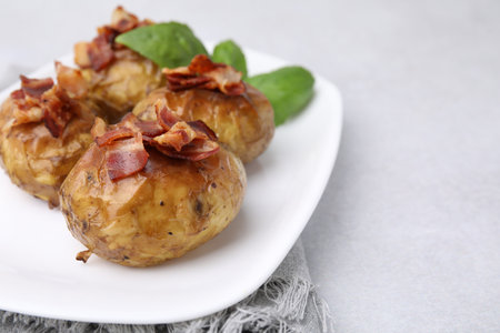 Delicious baked potatoes with bacon and basil on gray table, closeup. Space for textの写真素材