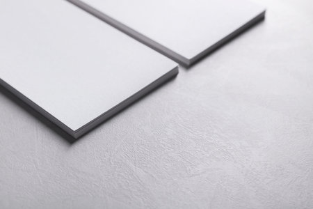 Blank business cards on light gray textured table, closeup. Mockup for design