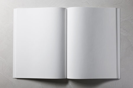 Open notebook with blank pages on gray textured background, top view. Mockup for design