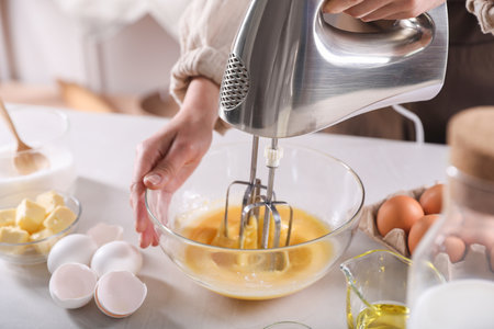 Woman making dough with mixer in bowl at table, closeupの写真素材