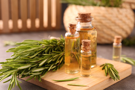 Essential oil in bottles and rosemary on gray tableの写真素材
