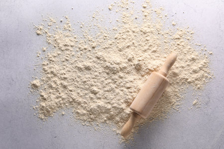 Pile of flour and rolling pin on light textured table, top viewの写真素材