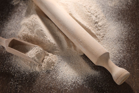 Pile of flour, rolling pin and scoop on wooden table, closeupの写真素材