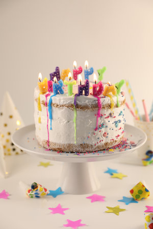 Tasty Birthday cake with burning candles and party decor on white tableの写真素材