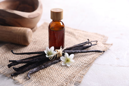 Vanilla pods, essential oil and flowers on light gray tableの写真素材