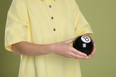 Man holding magic eight ball on olive background, closeupの写真素材