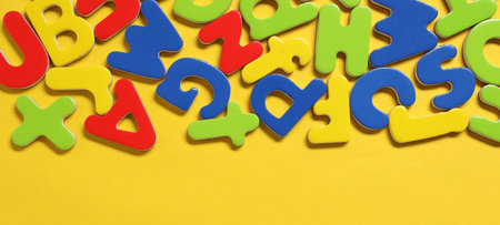 Learning alphabet. Magnetic letters on yellow background, flat lay. Space for textの写真素材