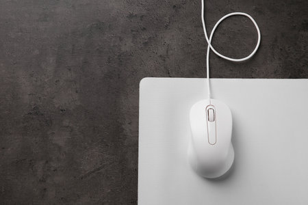 Wired mouse with mousepad on black textured table, top view. Space for text