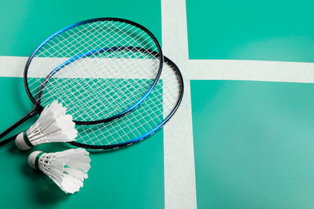Feather badminton shuttlecocks and rackets on green table. Space for textの写真素材