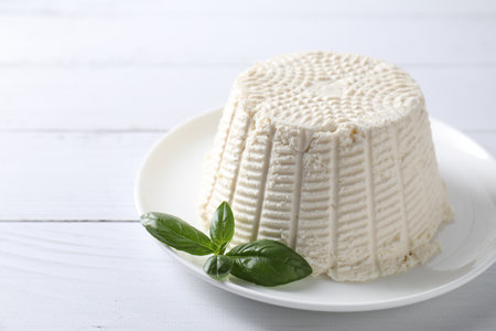 Fresh ricotta (cream cheese) and basil on white wooden tableの写真素材