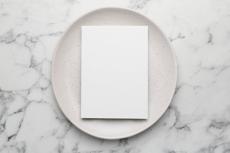 Empty menu and plate on white marble table, top view. Mockup for designの写真素材