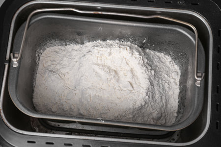 Modern bread maker with flour, closeup view