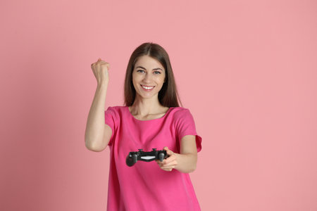 Happy woman with controller on pink backgroundの写真素材