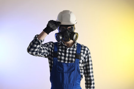 Worker in gas mask and helmet on color backgroundの写真素材