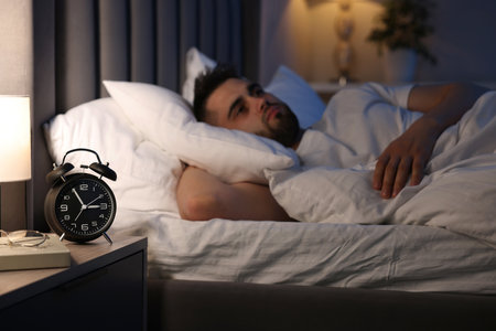 Frustrated man suffering from insomnia on bed, selective focusの写真素材