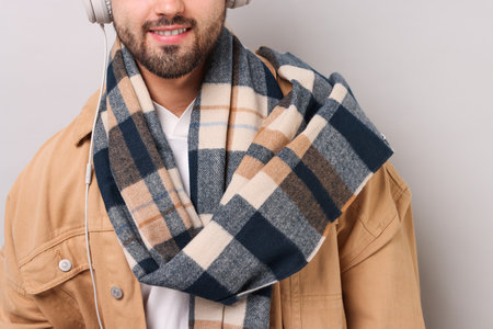 Smiling man in warm scarf on light grey background, closeupの写真素材