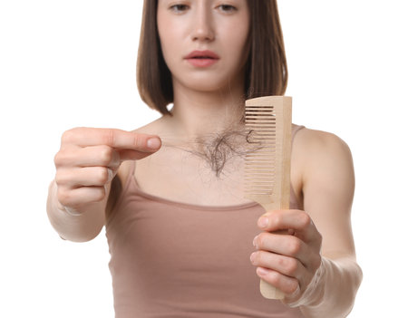 Woman taking her lost hair from comb on white background, selective focus. Alopecia problemの写真素材