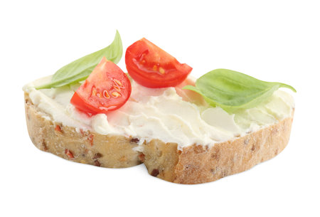 Piece of bread with cream cheese, basil leaves and tomato isolated on whiteの写真素材