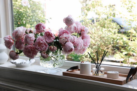Beautiful pink peonies in vase on window sill. Interior designの写真素材