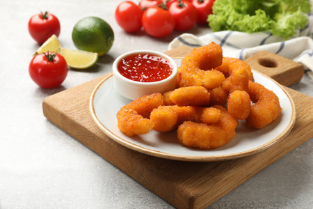 Delicious breaded fried shrimps served with sauce on light grey tableの写真素材