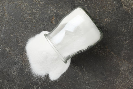 Baking soda in glass jar on gray table, top view