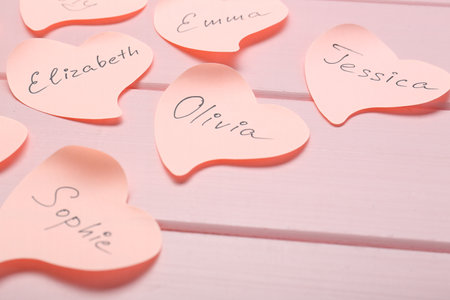 Paper stickers with different names on pink wooden table, closeup. Choosing baby's nameの写真素材
