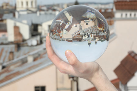 View of beautiful city street, overturned reflection. Man holding crystal ball outdoors, closeupの写真素材