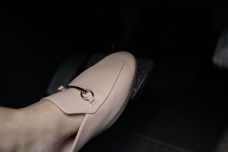 Woman pushing on pedal of car brake, closeup
