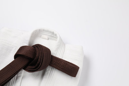 Brown karate belt and kimono on white background, top view. Space for textの写真素材