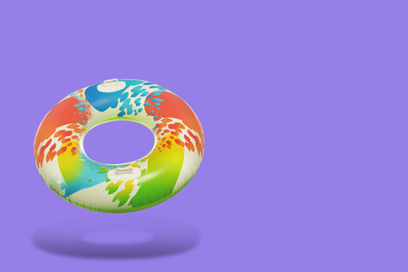 Colorful inflatable ring in air on purple background. Space for textの写真素材